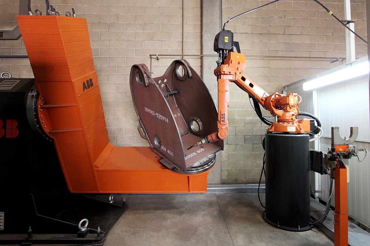 An orange ABB six-axis welding robot bent into a reaching pose.