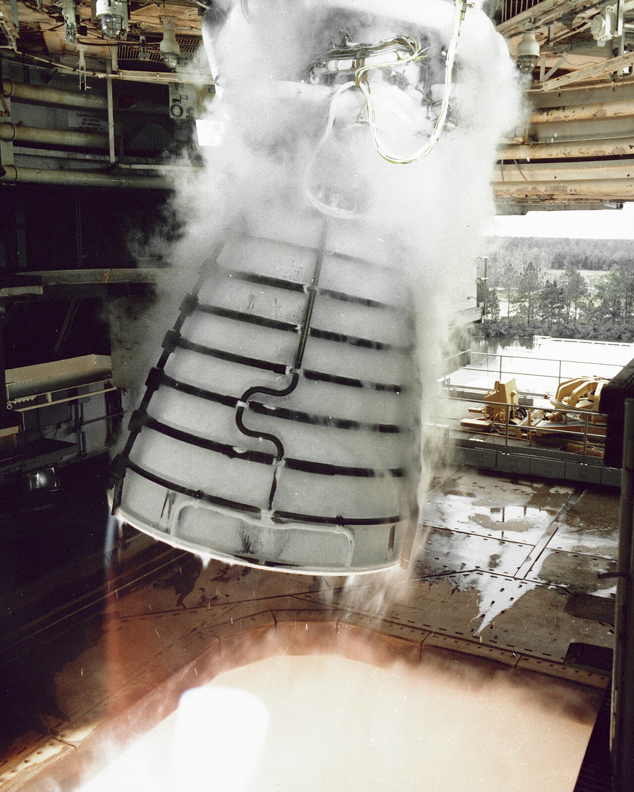 A Space Shuttle Main Engine firing while gimbaling on a test stand.